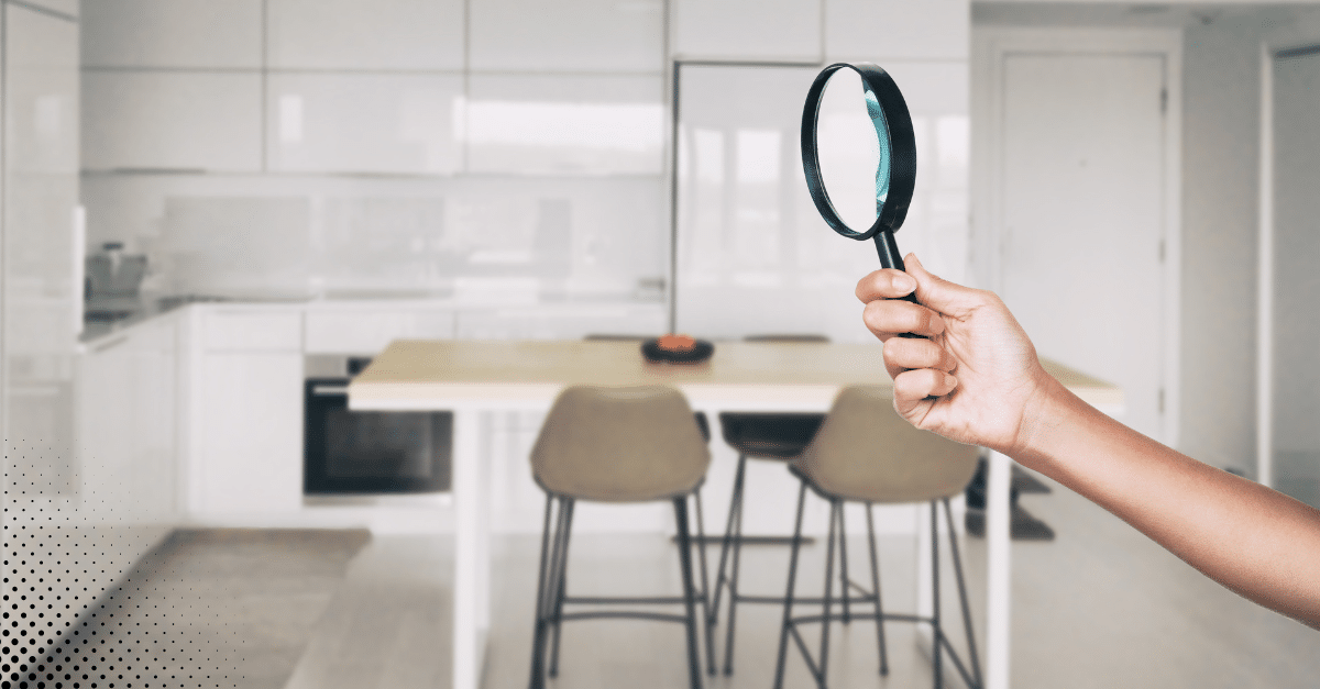 Hand holding magnifying glass in modern kitchen.
