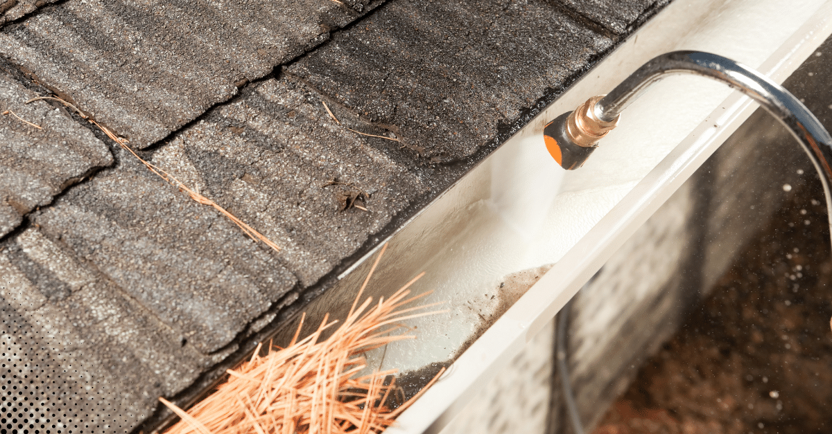 Pressure washing debris from a house gutter.