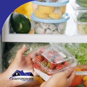 Hands placing a container of strawberries inside a refrigerator with fresh produce.