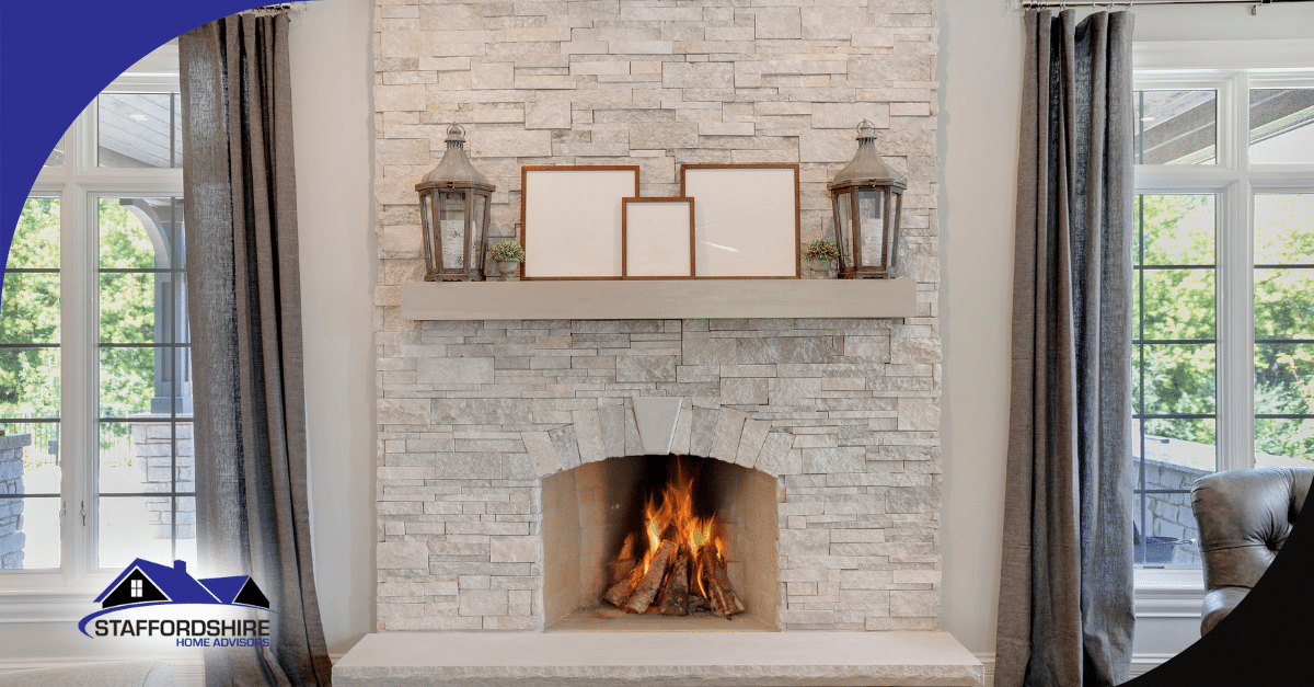 Modern stone fireplace with a burning fire, decorated mantel, and tall windows.